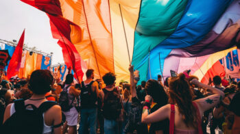 A crowd of people raising a big Pride flag